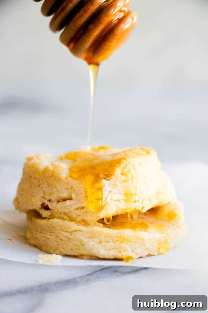 Fluffy Southern Biscuits from Scratch 2 A perfectly baked southern biscuit being generously drizzled with golden honey, highlighting its warm, inviting crust.