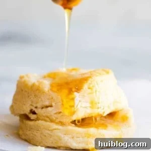 Fluffy Southern Biscuits from Scratch 15 A biscuit being drizzled with honey.