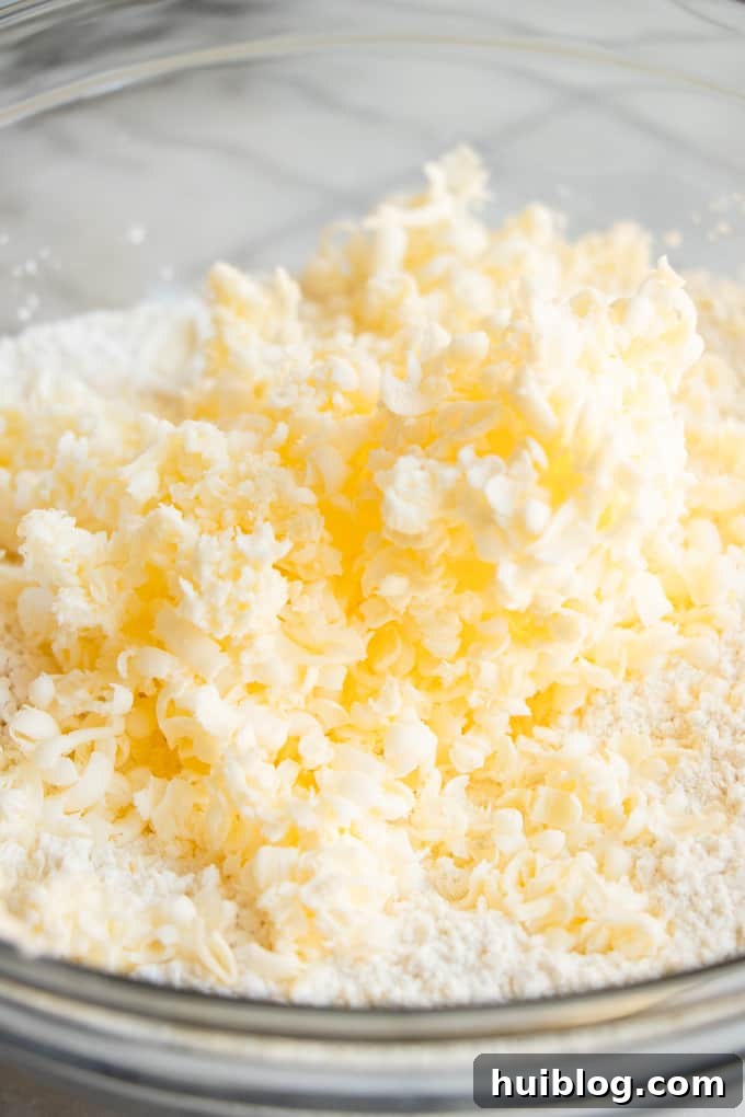 Fluffy Southern Biscuits from Scratch 4 Finely grated cold butter added to a bowl of dry ingredients, showcasing the initial step of combining elements for delicious homemade biscuits.