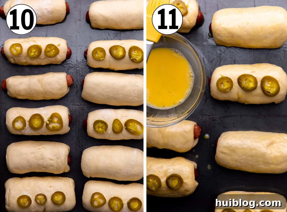 Texas Klobasnek Sausage Kolaches 9 Baked sausage kolaches on a baking sheet, topped with jalapeños and being brushed with an egg wash for a golden finish.