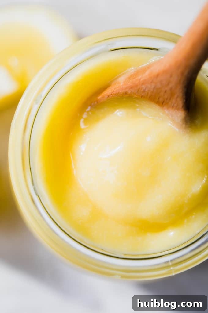 Overhead view of a glass jar filled with lemon curd, showing the smooth, creamy texture.
