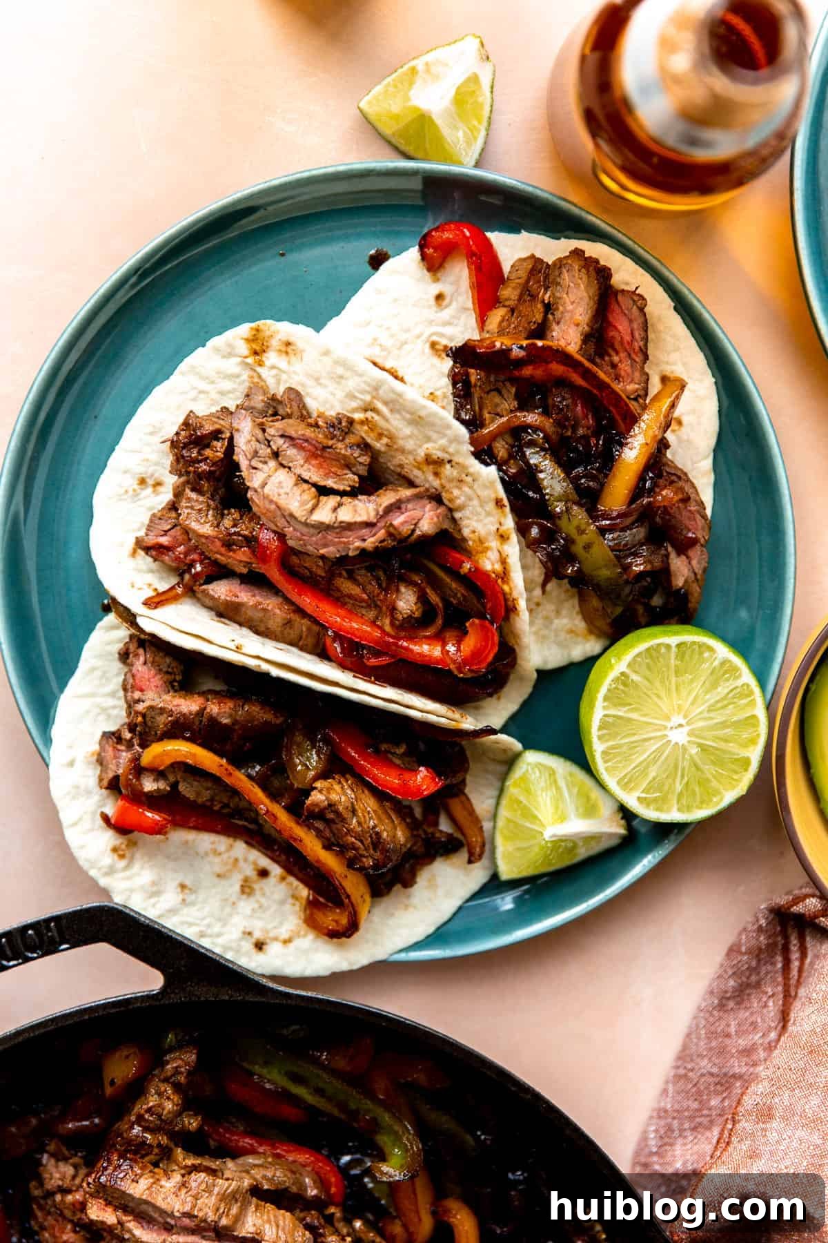 Close-up of a sizzling cast iron skillet filled with colorful steak fajitas, showcasing the vibrant ingredients.