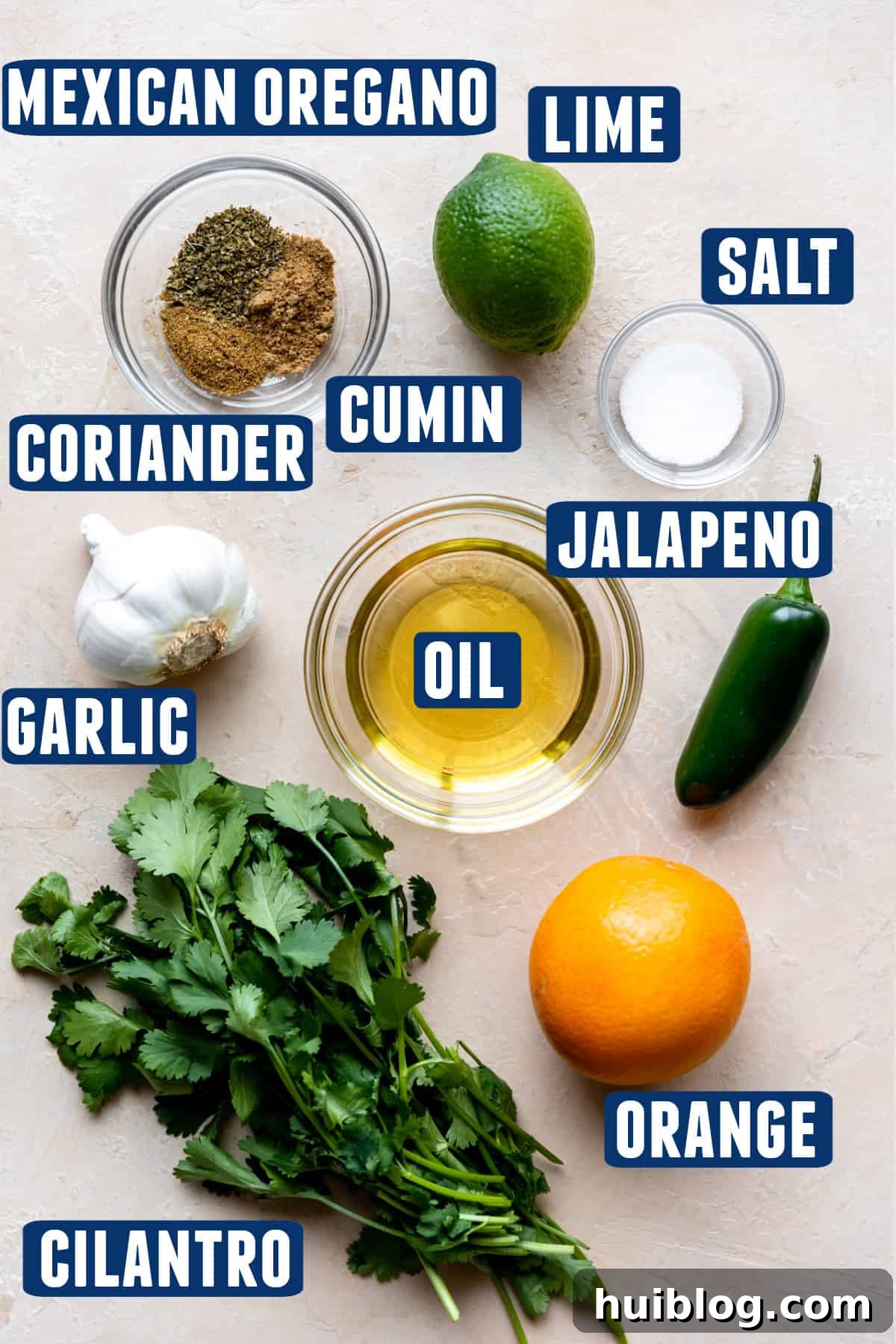 Fresh ingredients needed to make a vibrant carnitas marinade laid out on a kitchen counter, showcasing bright citrus, green herbs, and spices.