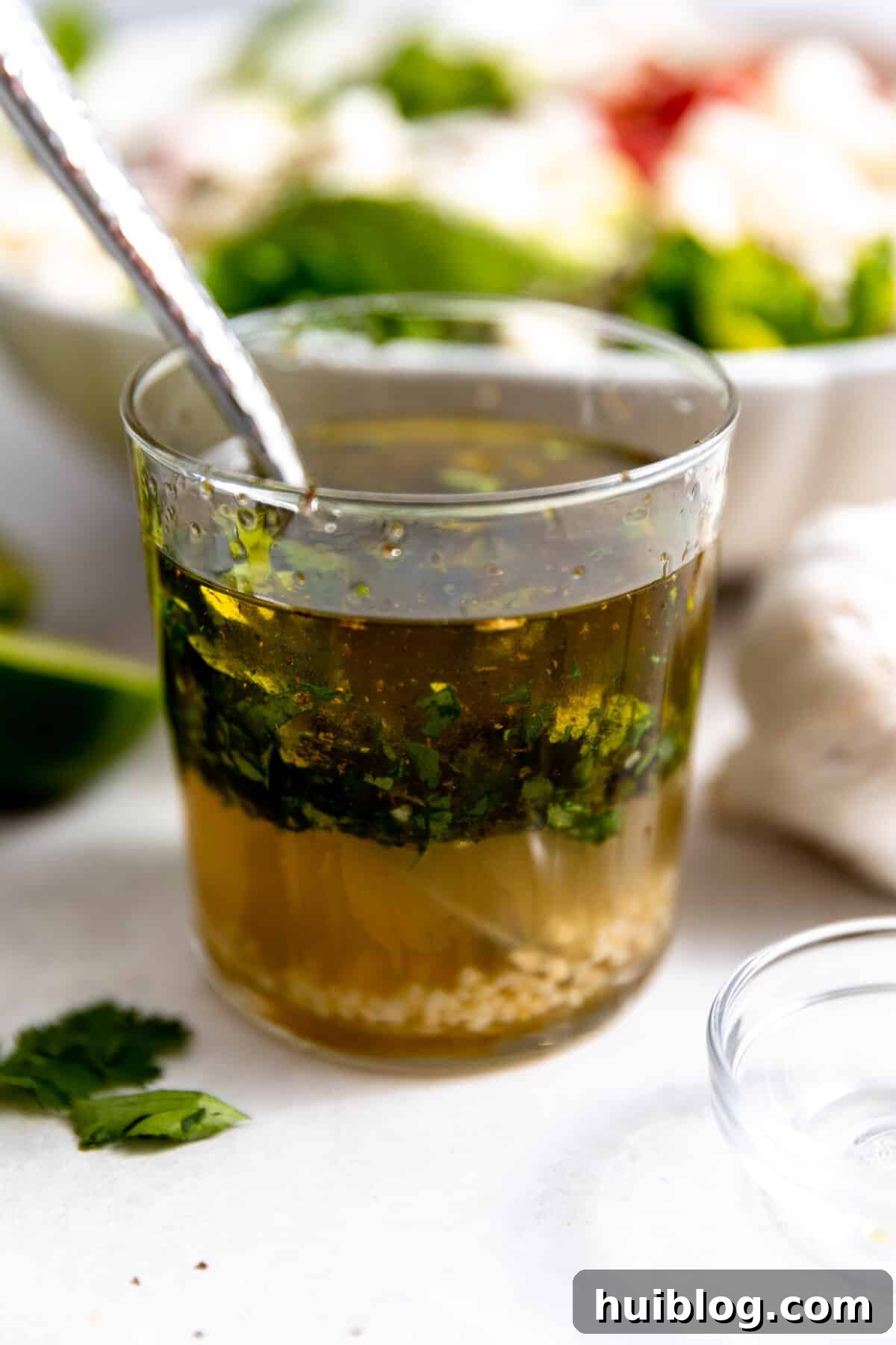 Fiesta Salad Bowl 4 Cup of homemade honey lime vinaigrette with a spoon resting in it, ready to be poured over salad.