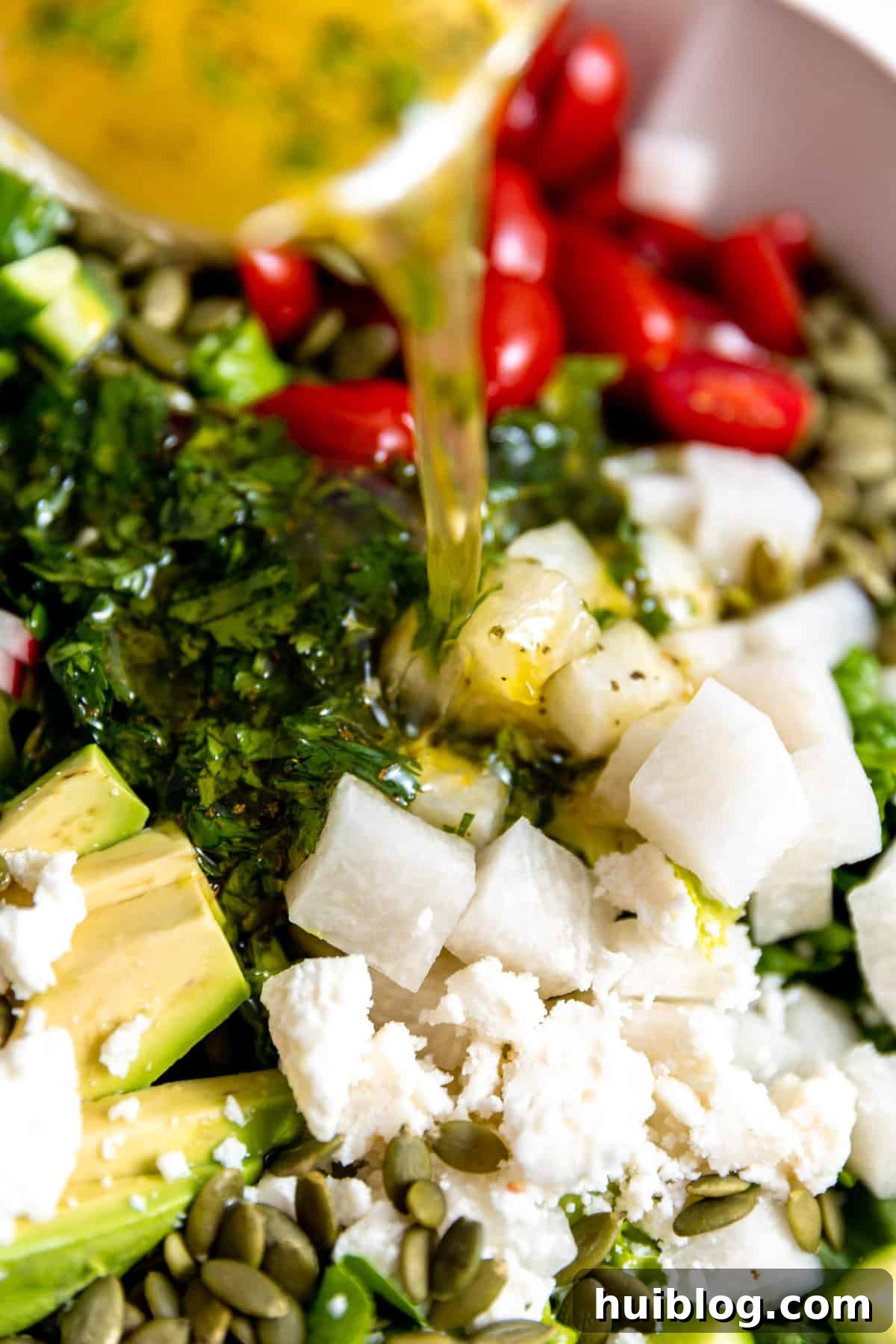 Fiesta Salad Bowl 6 Dressing being poured over a freshly assembled Mexican salad in a white bowl.