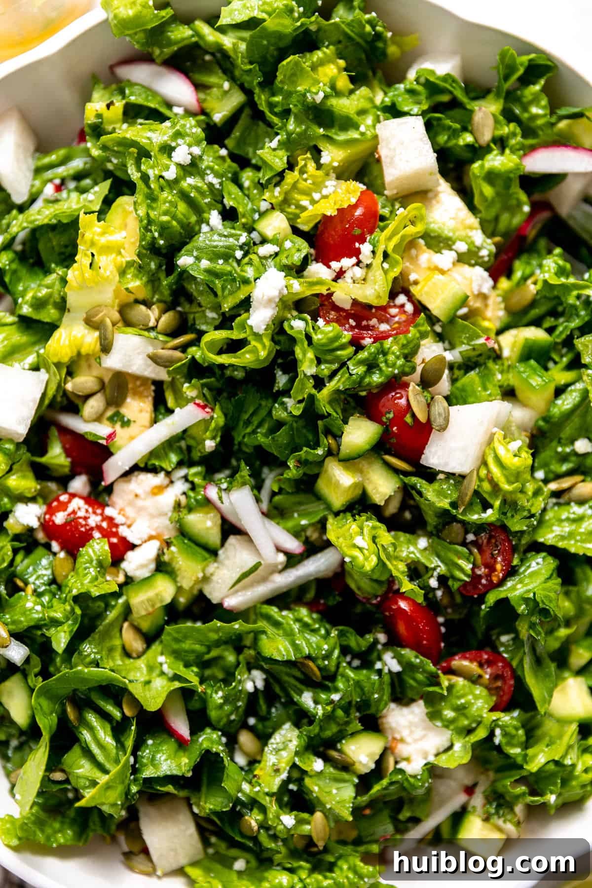 Fiesta Salad Bowl 8 Up close shot of a Mexican salad mixed with dressing in a white bowl, showing all the vibrant ingredients.