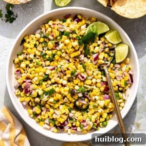 Bowl of vibrant roasted corn salsa, adorned with fresh lime wedges for a zesty touch.