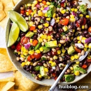 Bowl of colorful Texas Caviar, a black-eyed pea dip, artfully garnished with a fresh lime wedge.