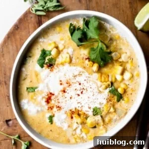 Bowl of creamy Mexican Corn Chowder topped with a swirl of crema and crumbled queso fresco, garnished with fresh herbs.