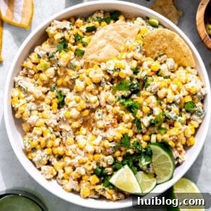 Bowl of Mexican Corn Dip served with crispy tortilla chips, ready for dipping.