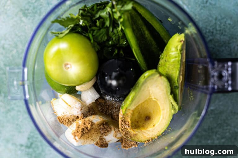 All ingredients for avocado salsa in a food processor, ready to blend.