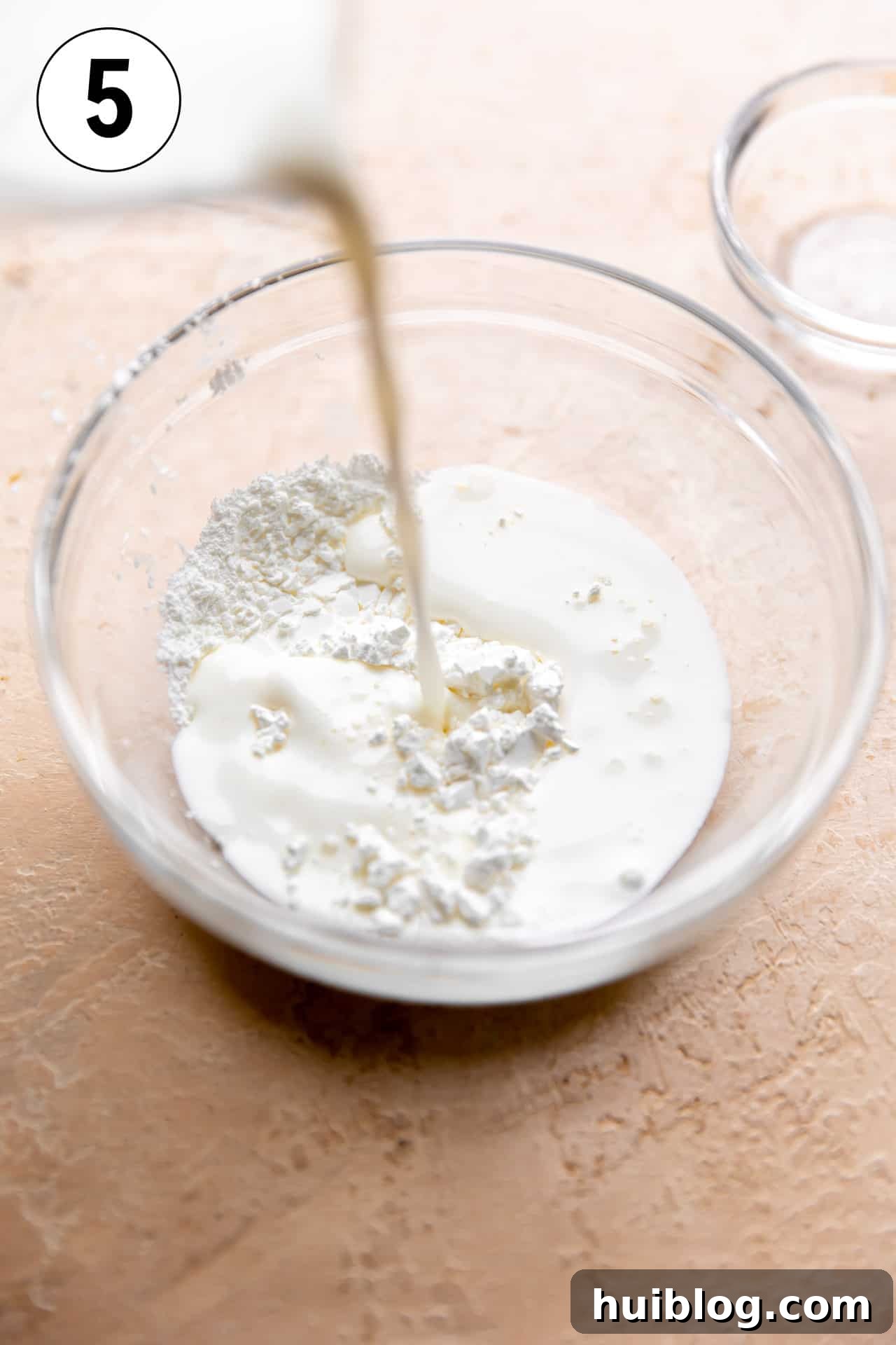 A small bowl showing milk being combined with cornstarch to create a slurry, a key step for thickening the ham bone soup to a creamy consistency.