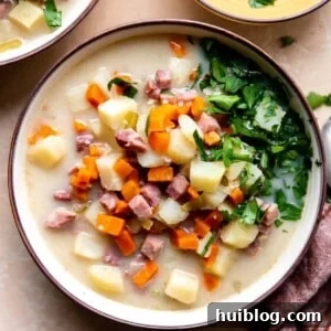 A bowl of creamy ham and potato soup topped with fresh parsley, ready to be served.