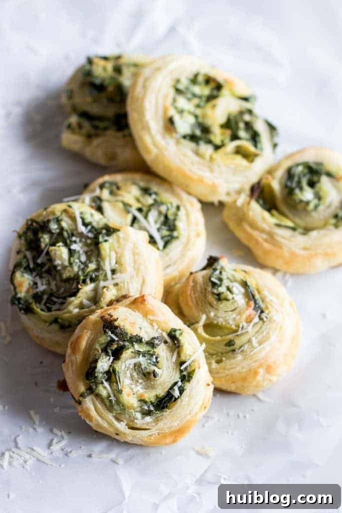 Flaky Spinach Artichoke Swirls 5 Several Puff Pastry Spinach and Artichoke Pinwheels cooling on a rack, showcasing their uniform shape and golden crust.