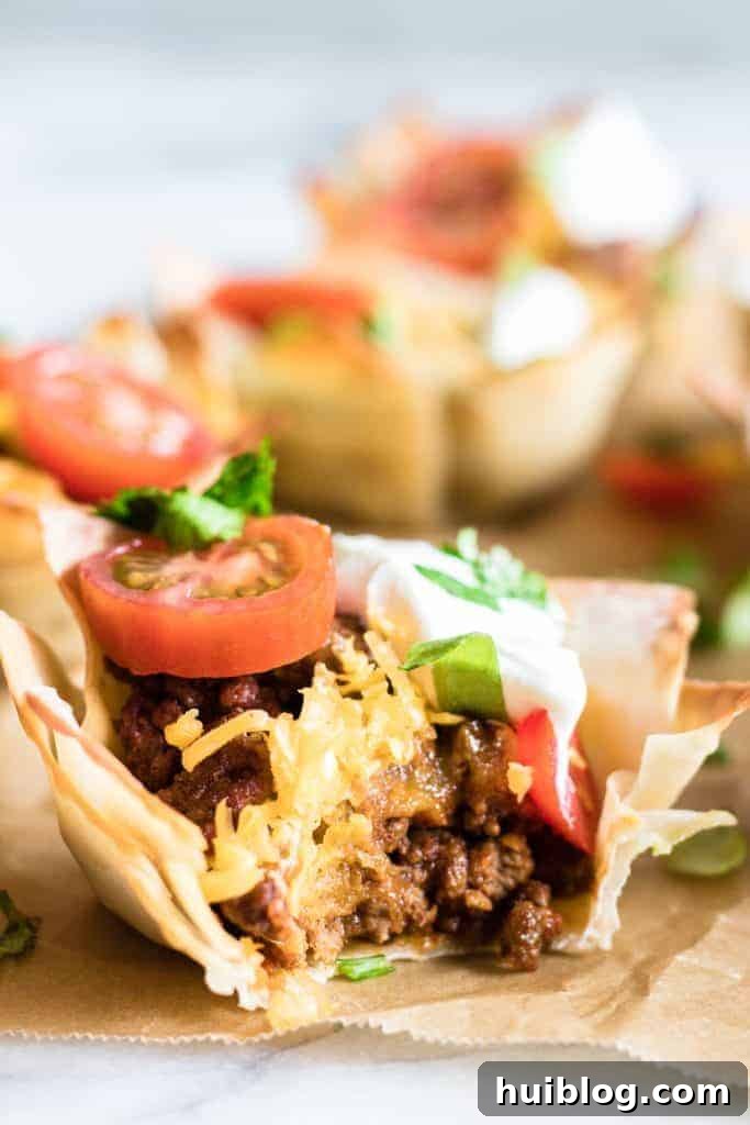 Taco Poppers 2 Bit into Taco Cup showing juicy taco meat, melty cheese, shredded lettuce, tomato and sprinkled cilantro.