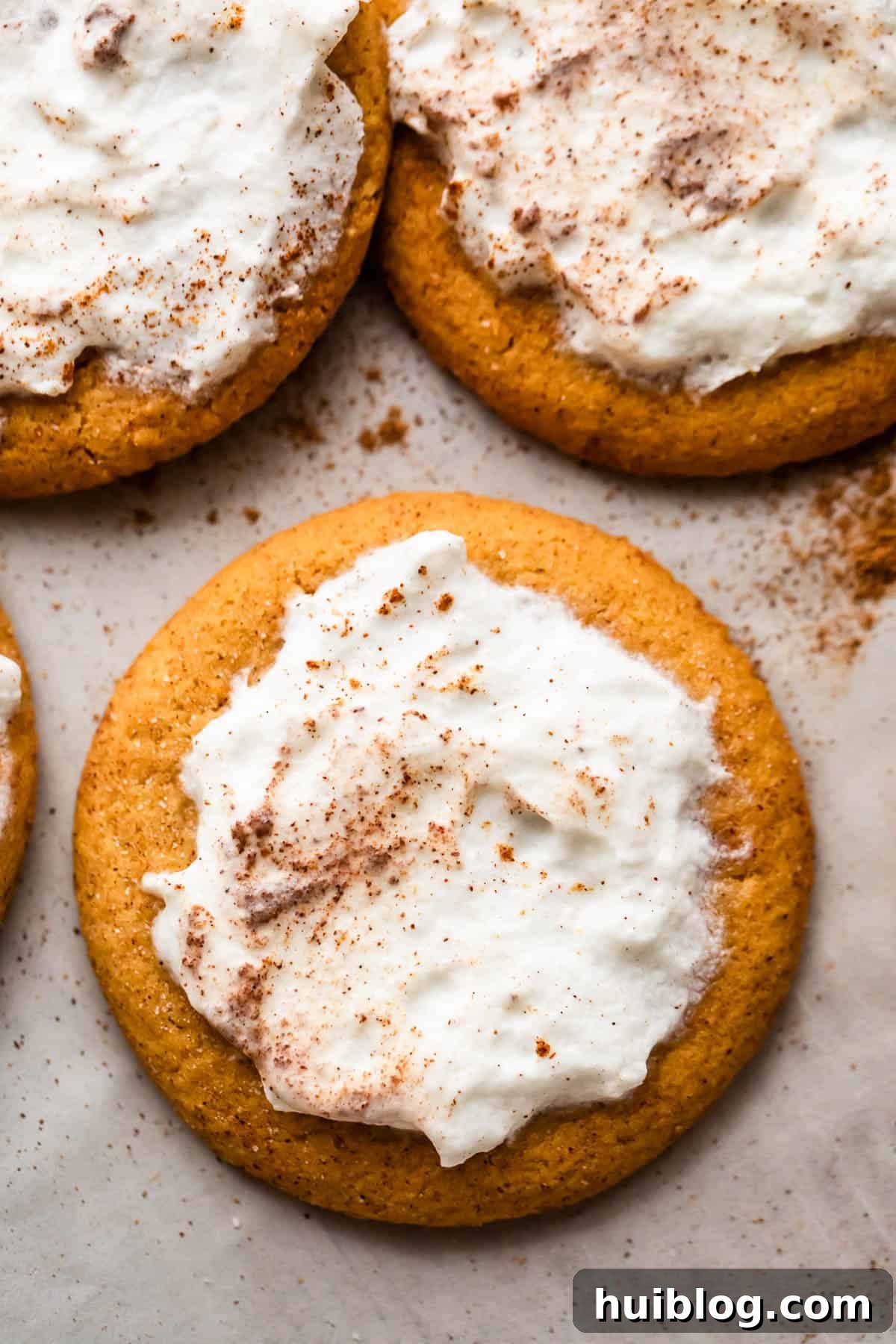 overhead shot of three pumpkin cookies topped with cream cheese frosting.