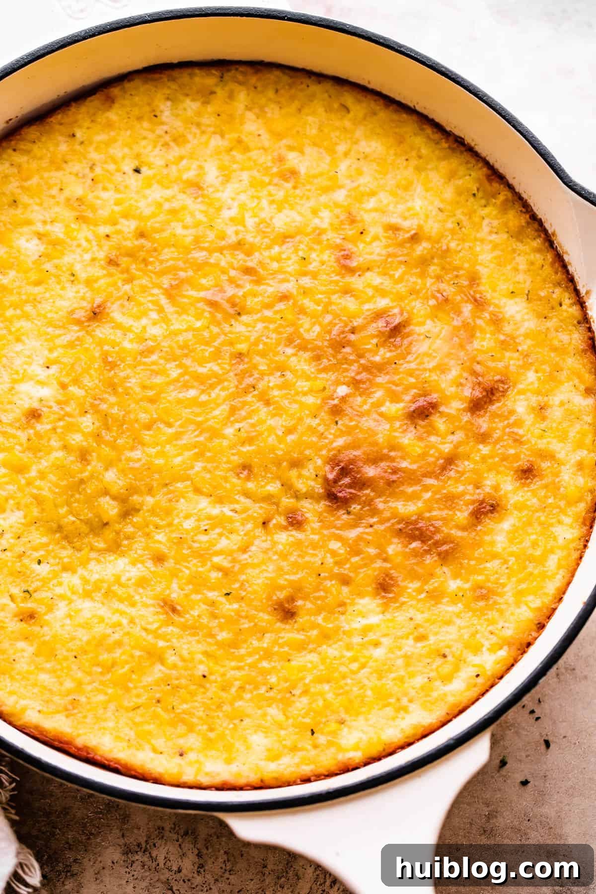 A large skillet filled with freshly baked, golden-brown corn pudding, ready to be served.