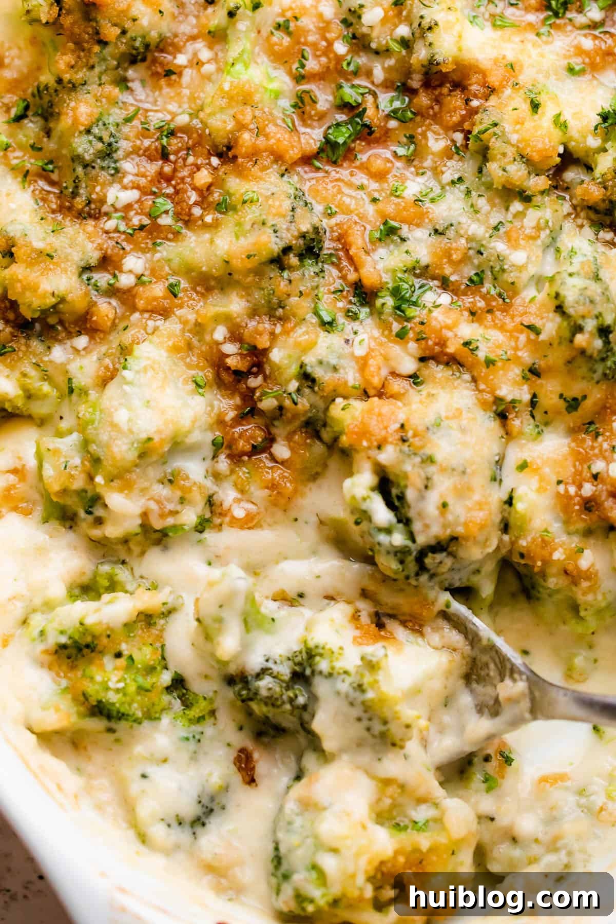 Up close overhead shot of an oval baking dish filled with golden-brown and bubbly Creamy, Cheesy Broccoli Casserole, showcasing the crisp topping.