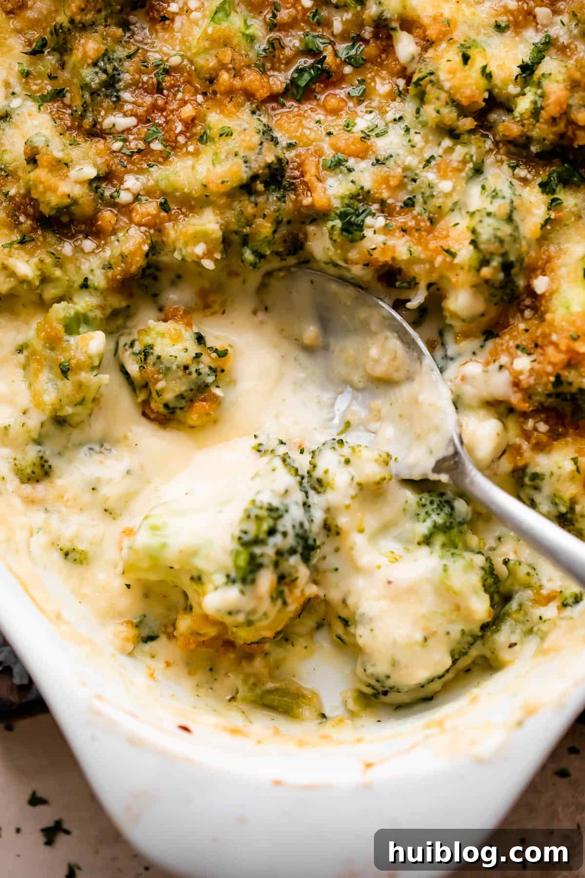 Up close overhead shot of an oval baking dish with Creamy, Cheesy Broccoli Casserole, perfectly browned and bubbly, ready to be served.