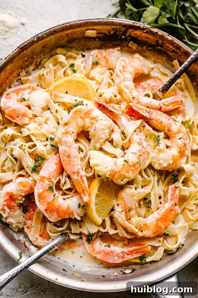 Creamy shrimp Alfredo pasta with my easy homemade Alfredo sauce! Made in only one pot, this pasta dinner idea is ready in under 30 minutes! Creamy Shrimp Alfredo Pasta with serving spoons ready to be eaten