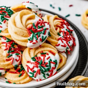 A small dessert plate stacked on top of several other plates, and piled with iced butter cookies.