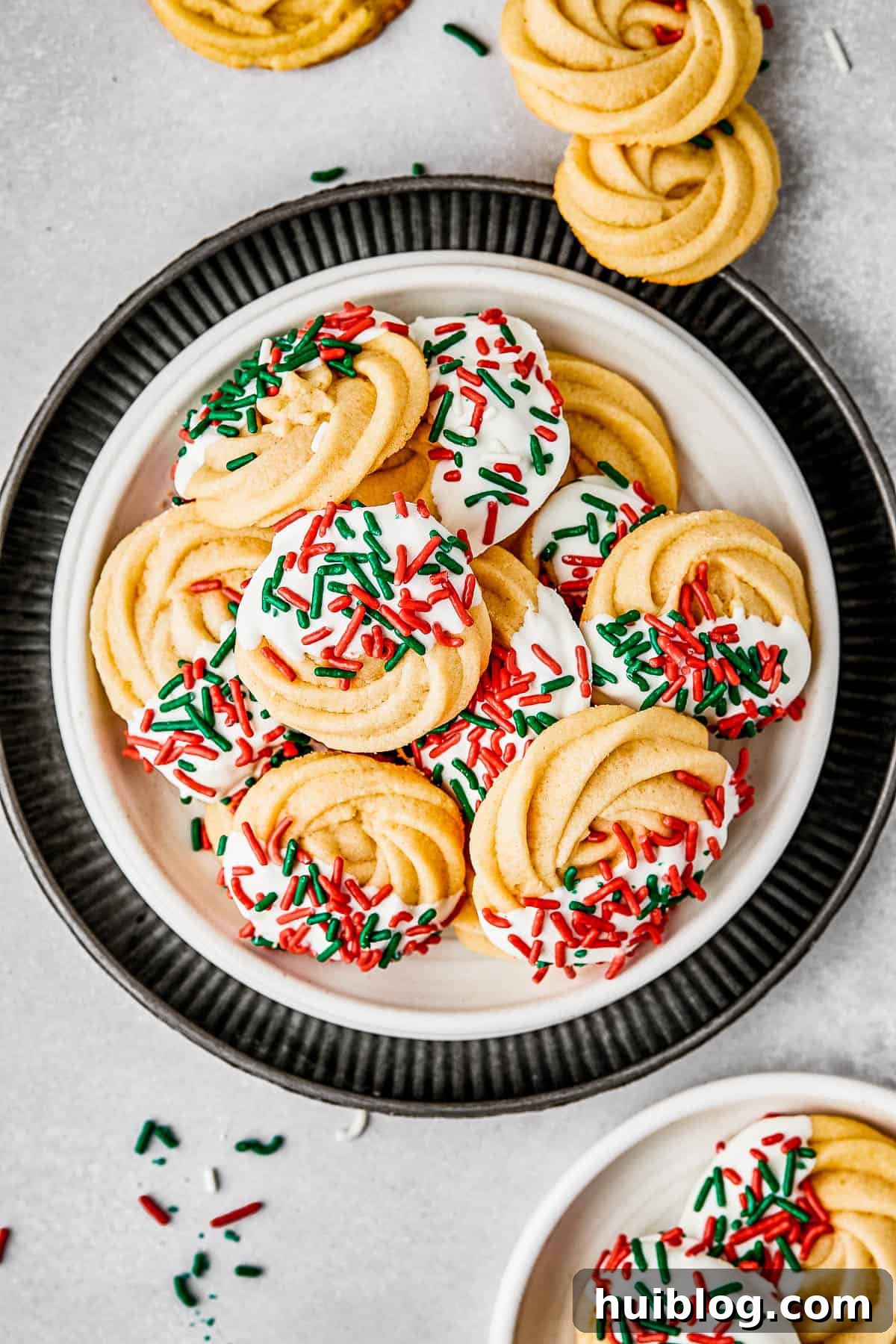 An overhead shot of a small dessert plate stacked on top of several other plates, adorned with beautifully iced butter cookies. The arrangement suggests a delightful treat ready to be savored or shared.