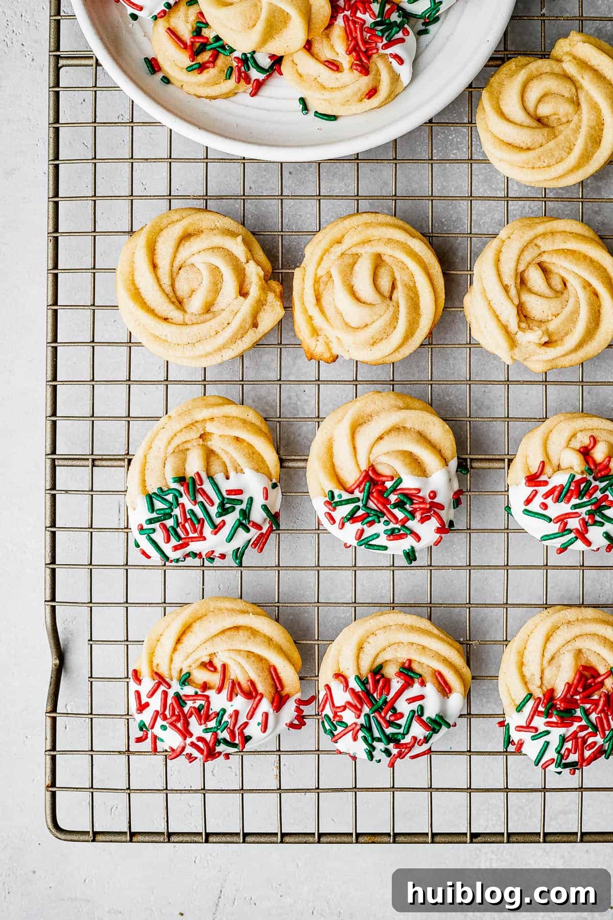 Decorated butter cookies artfully drying on a wire cookie rack, showcasing various icing designs and sprinkles, ready for serving or packaging.