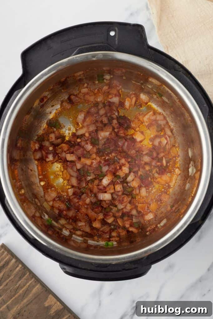 Overhead shot of an Instant Pot with sautéed vegetables, tomato paste, and spices fragrant in the pot.