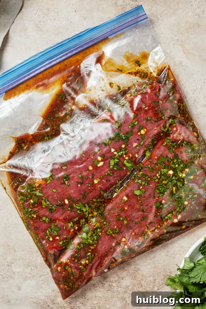 A zip-top bag with flank steak and marinade inside, ready for refrigeration.
