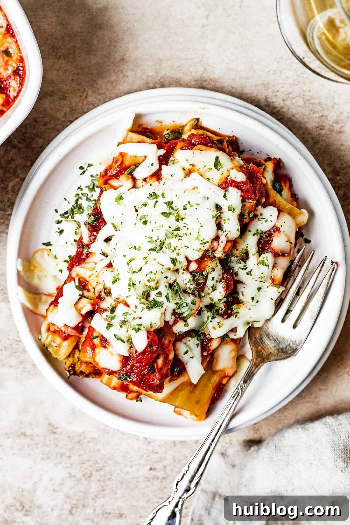 An overhead shot showcasing three beautifully stuffed manicotti shells resting on a small, elegant plate, ready to be enjoyed.