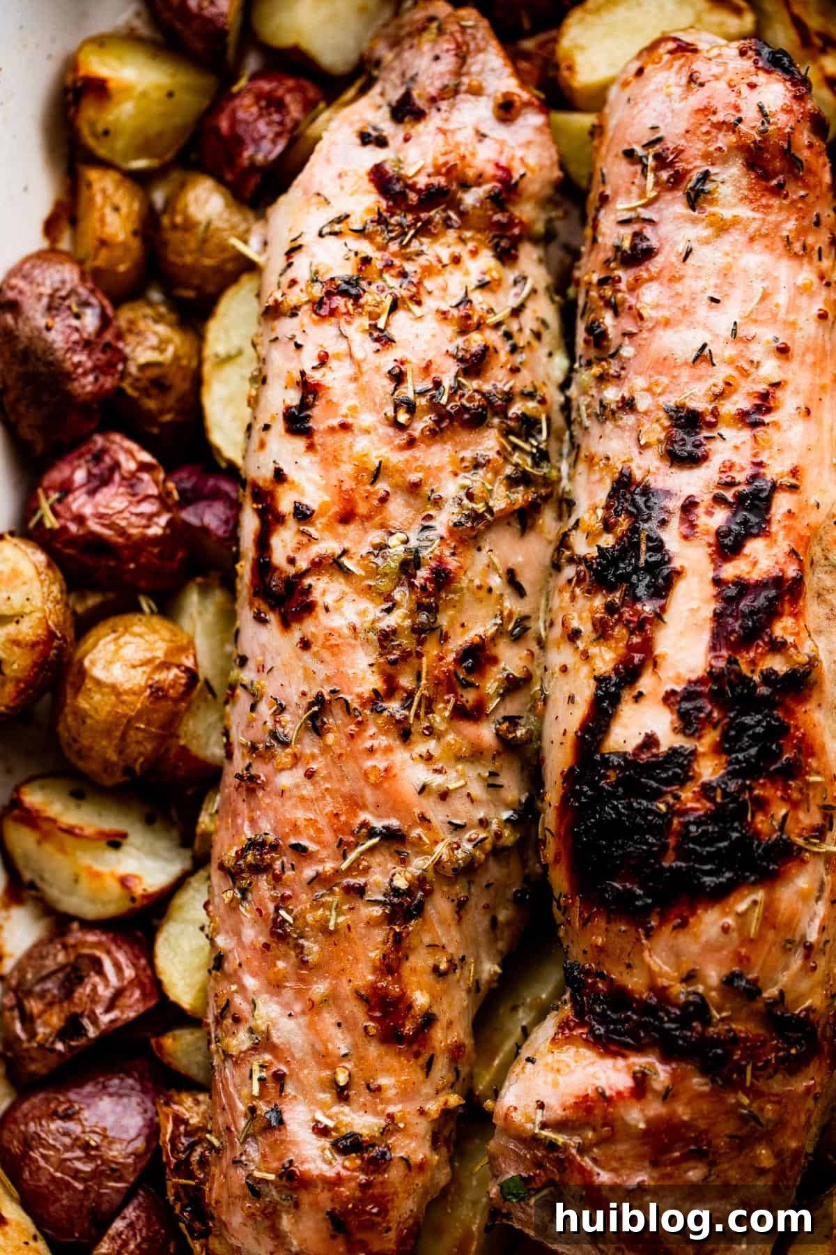 roasted pork tenderloins set on top of cooked baby potatoes