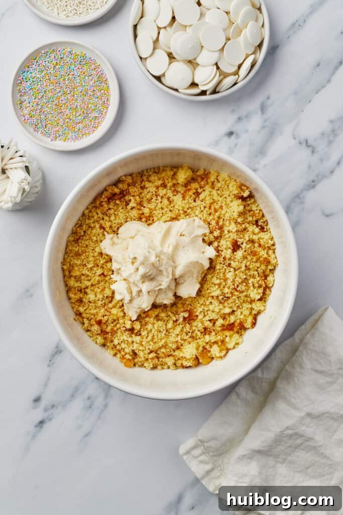 A close-up of cake crumbs and frosting mixed together in a bowl, forming a pliable dough for cake pops.