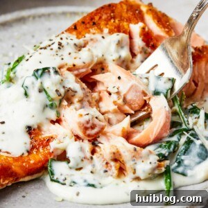 Pan-Seared Salmon with Creamy Spinach 12 A serving of salmon florentine. A bite of the salmon is being lifted toward the camera on a fork.