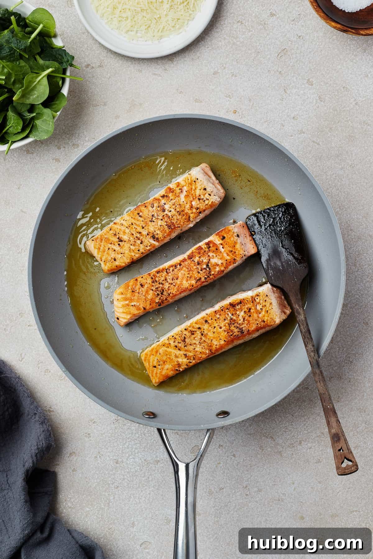 Pan-Seared Salmon with Creamy Spinach 5 Salmon fillets cooking in a skillet.