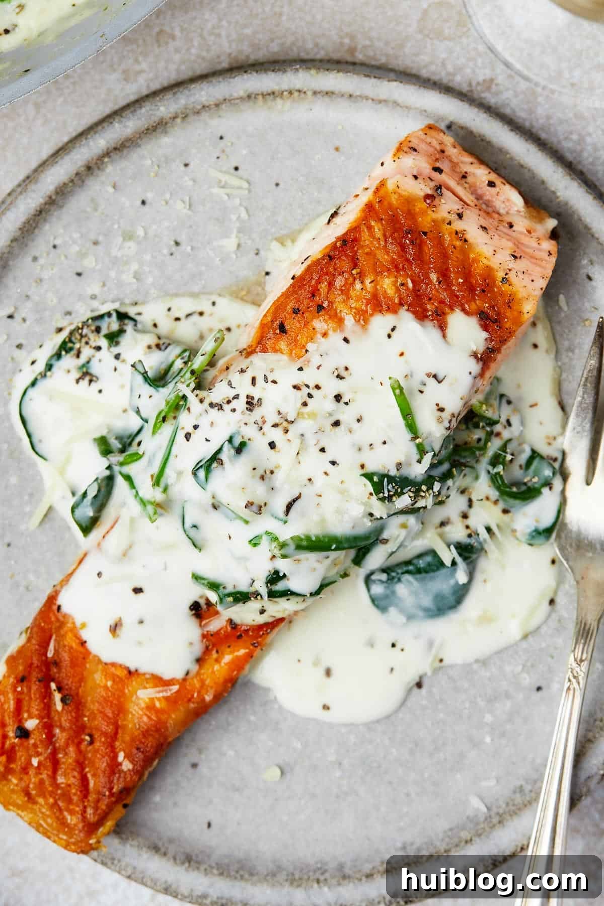 Pan-Seared Salmon with Creamy Spinach 10 A salmon fillet topped with creamy sauce on a small plate.