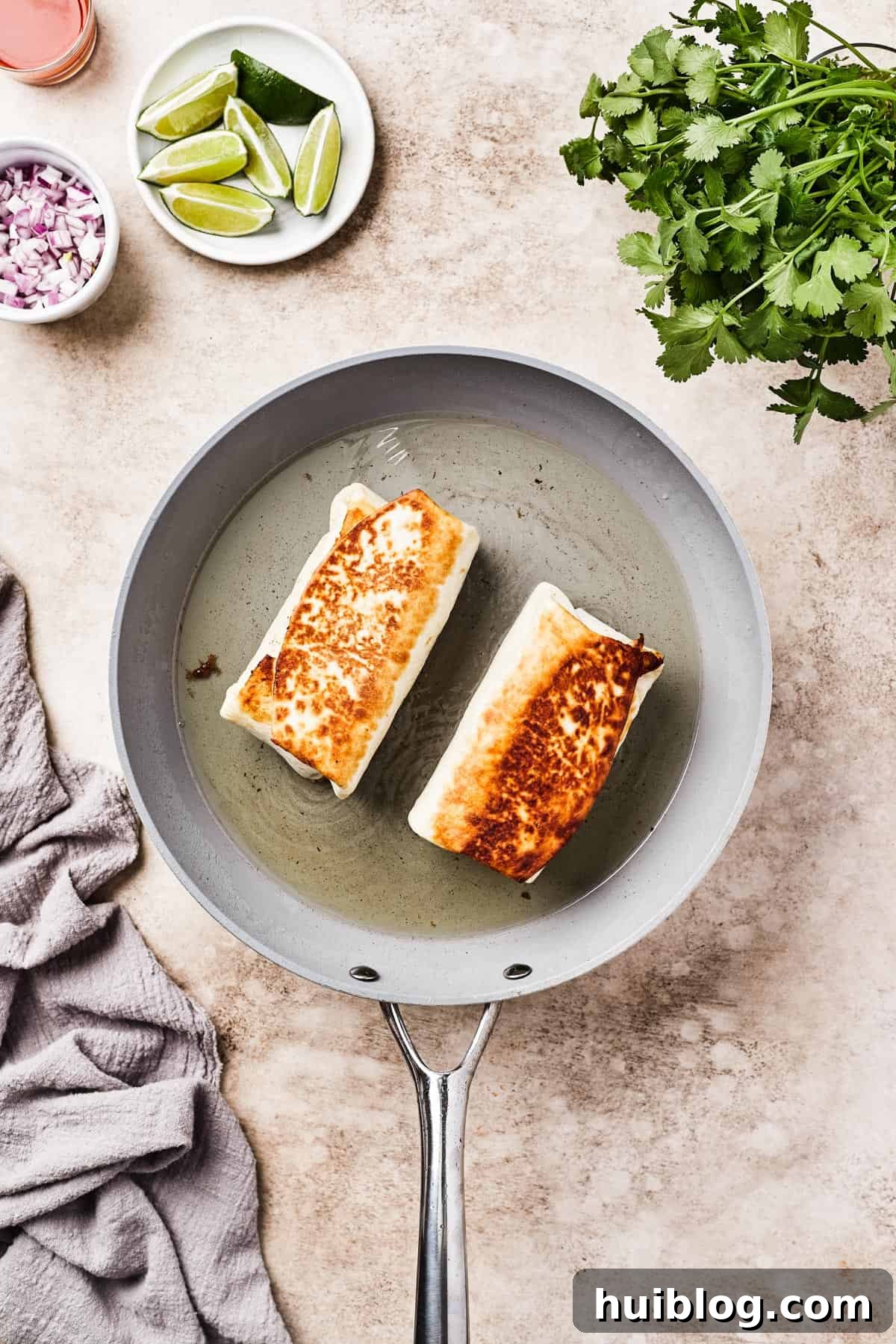 Fried burritos in a skillet with oil.