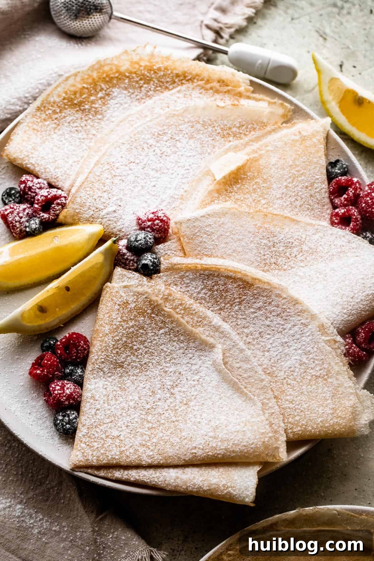 Whip Up Perfect French Crepes 2 Overhead shot of freshly made homemade crepes, artfully folded and lightly dusted with powdered sugar, ready to be enjoyed.