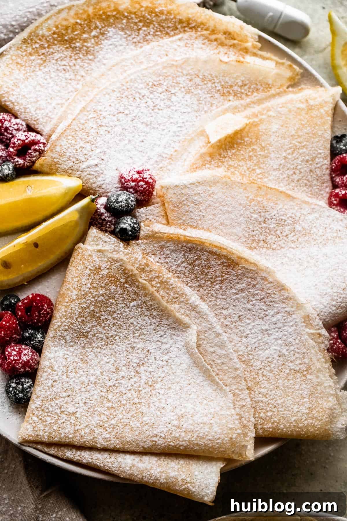 Whip Up Perfect French Crepes 6 Overhead shot of two homemade crepes, elegantly folded in half and dusted with powdered sugar, ready to be served.