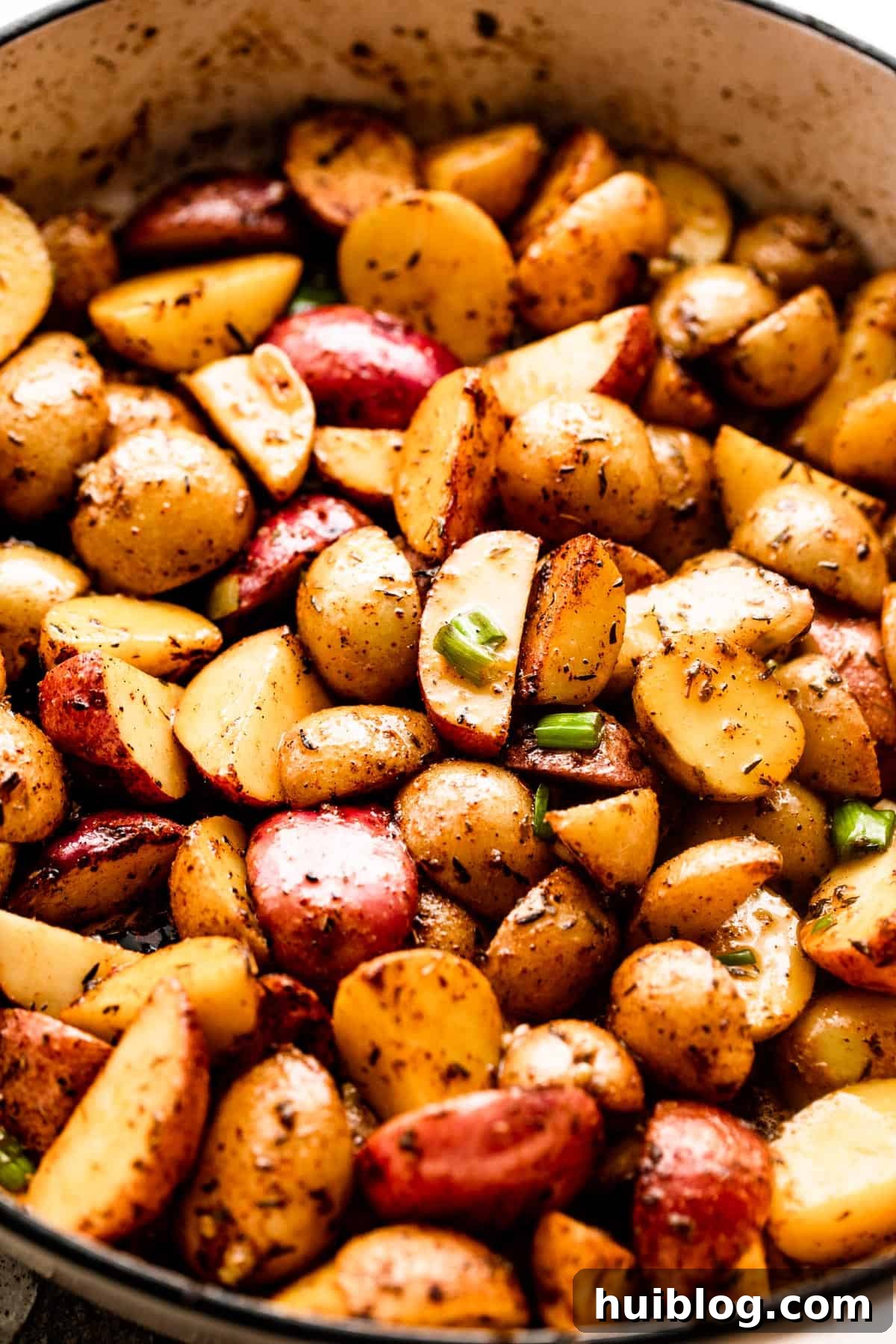 quartered small potatoes in a white skillet, ready for roasting.