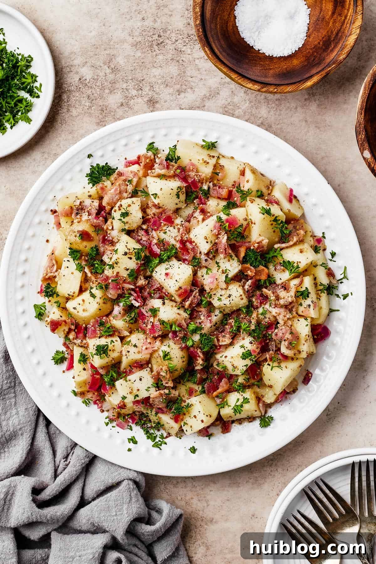 A plate of warm potato salad with herbs and bacon.