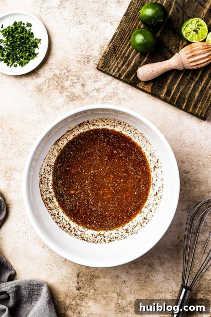 A vibrant citrus and spice mixture prepared in a white bowl, ready for the carnitas.
