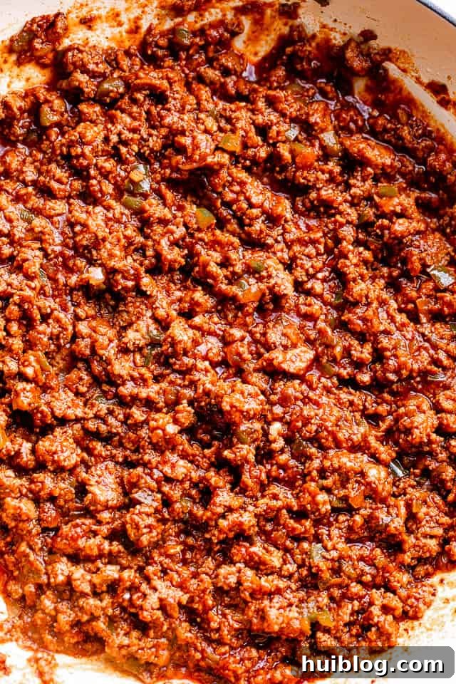 Ground beef in a skillet mixed with ketchup and brown sugar.