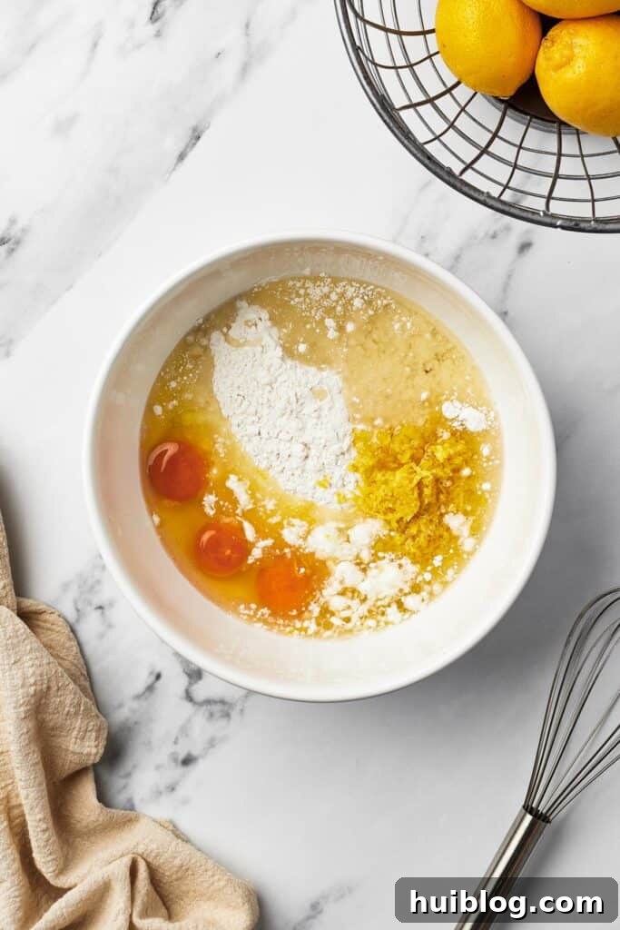 A close-up shot of a mixing bowl containing yellow cake mix, three raw eggs, water, and oil, ready to be combined into a smooth batter.
