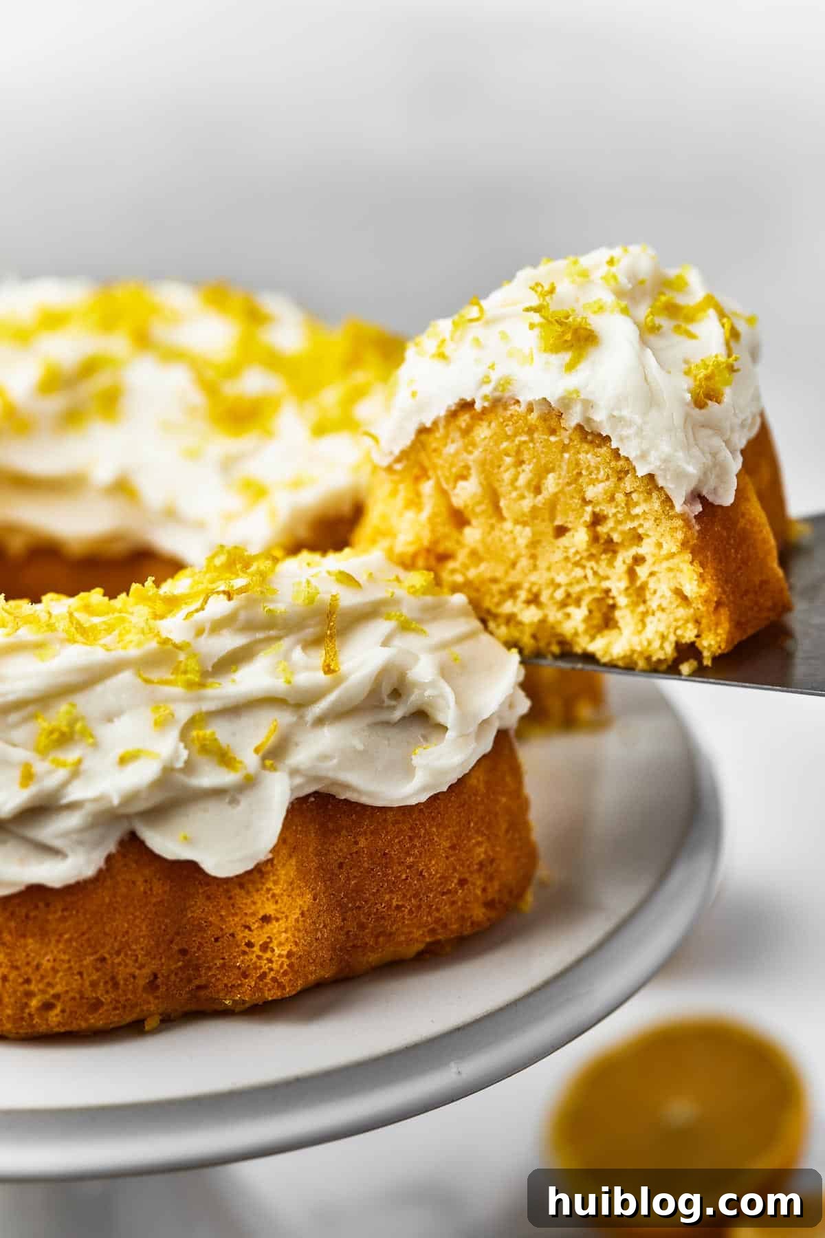 A freshly baked Bundt cake, still on its platter, as a single slice is gracefully removed with a cake server, ready to be enjoyed.