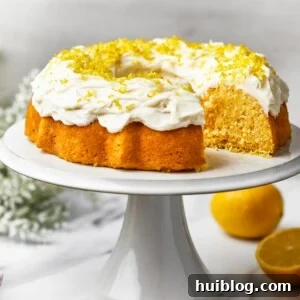 A beautifully baked lemon Bundt cake rests on a pristine white platter, with one perfect slice carefully removed, revealing its moist, tender interior.