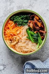 Korean Beef and Glass Noodle Japchae 6 A large mixing bowl filled with vibrant Japchae: glass noodles, beef, mushrooms, green onions, carrots, and spinach, ready for final seasoning and tossing.
