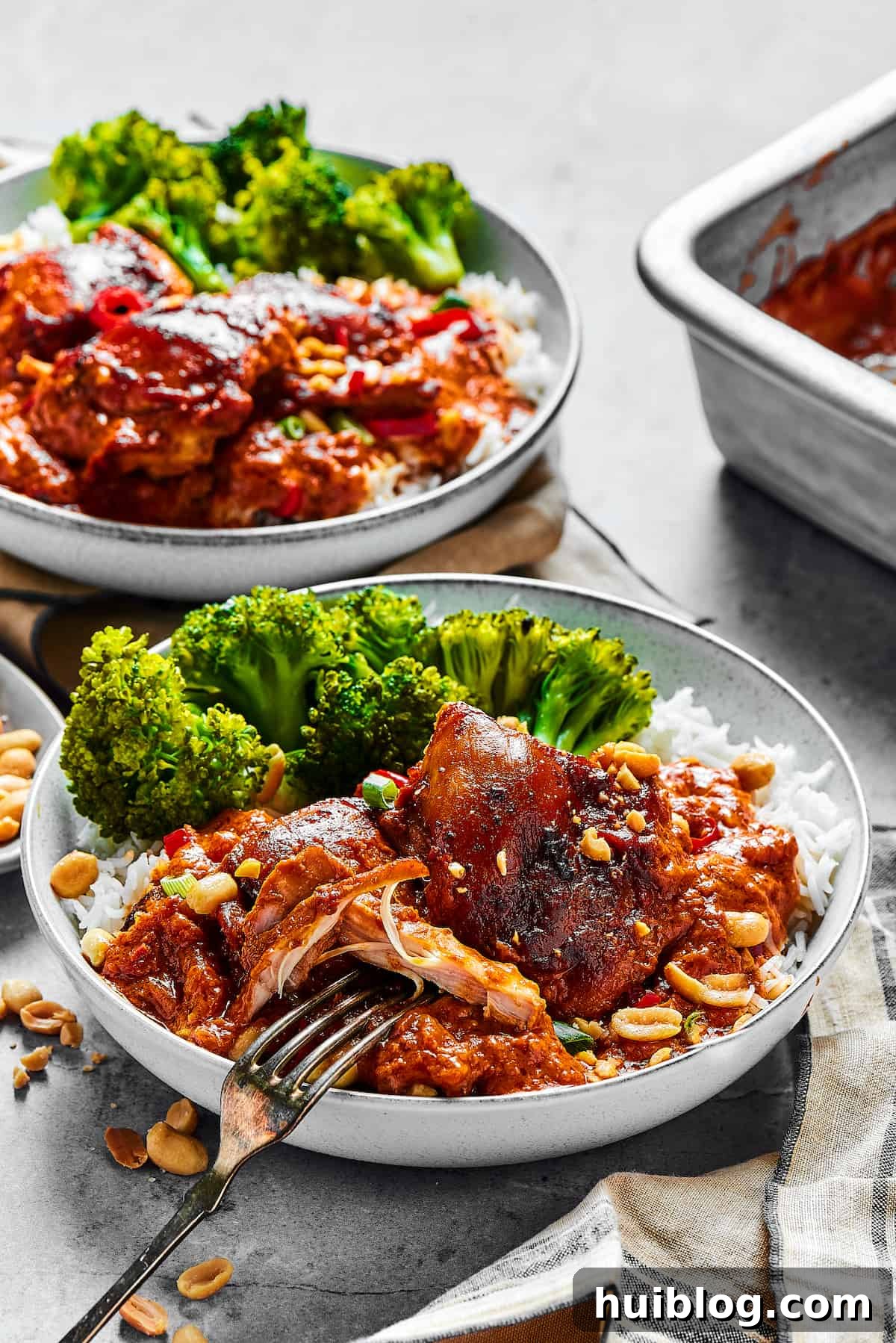 Two Plates of Peanut Butter Chicken Two beautifully plated portions of saucy Peanut Butter Chicken served with vibrant green vegetables, ready to be enjoyed.