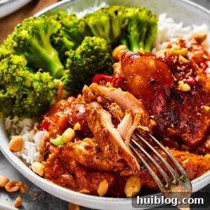Rich Peanut Glazed Chicken 9 A close-up shot of a chicken thigh cooked in peanut sauce, with a fork pulling away a bite.