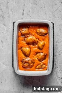 Rich Peanut Glazed Chicken 7 A baking dish full of creamy tomato peanut sauce, with chicken thighs arranged in the sauce.