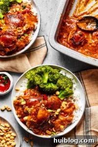 Creamy Peanut Butter Chicken 7 Peanut Butter Chicken served with steamed broccoli over rice on a plate, with the baking dish and garnishes visible on a nearby table, inviting you to enjoy.